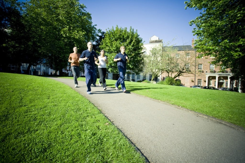 Group running in a park with house in the background