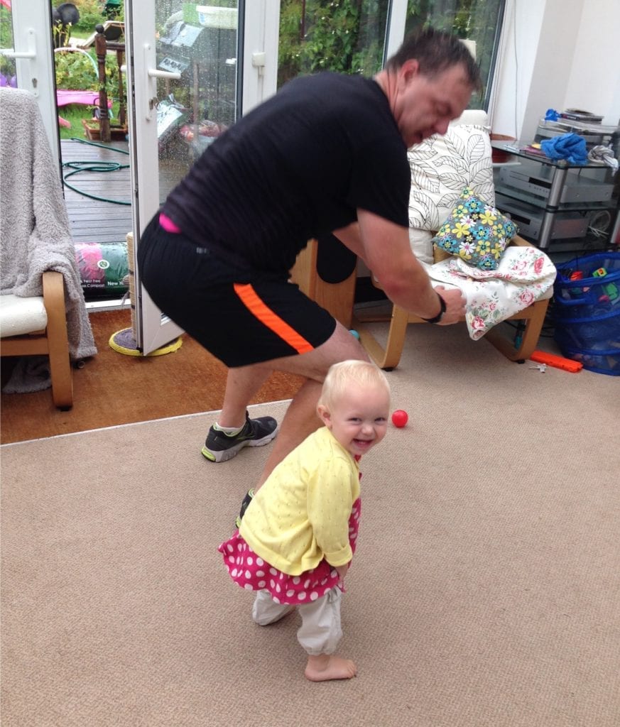 Man squatting next to his daughter influencing kids to exercise
