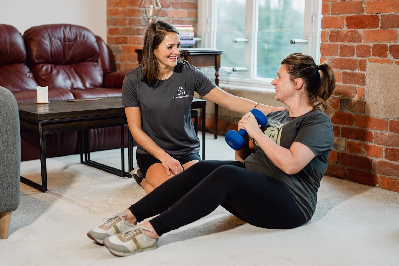 Katie showing her personal training client a seated dumbbell russian twist